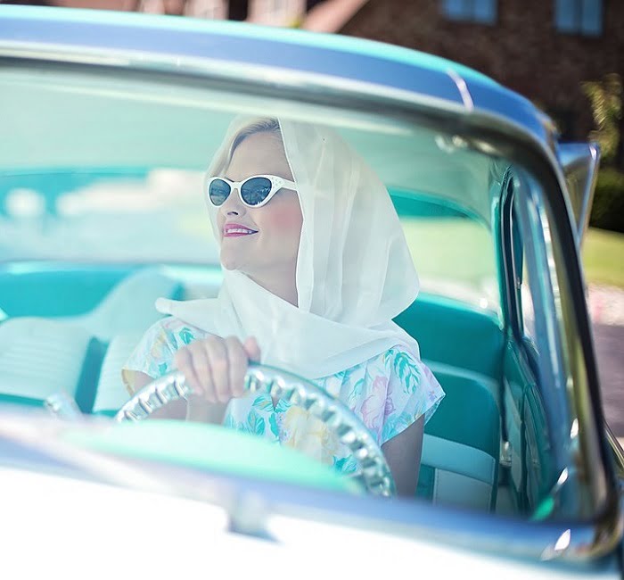 femme au look des années 50 dans une voiture citadine